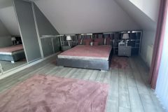 Aranżacja sypialni na poddaszu z łóżkiem Waszyngton i zagłówkiem na wymiar na całej ścianie