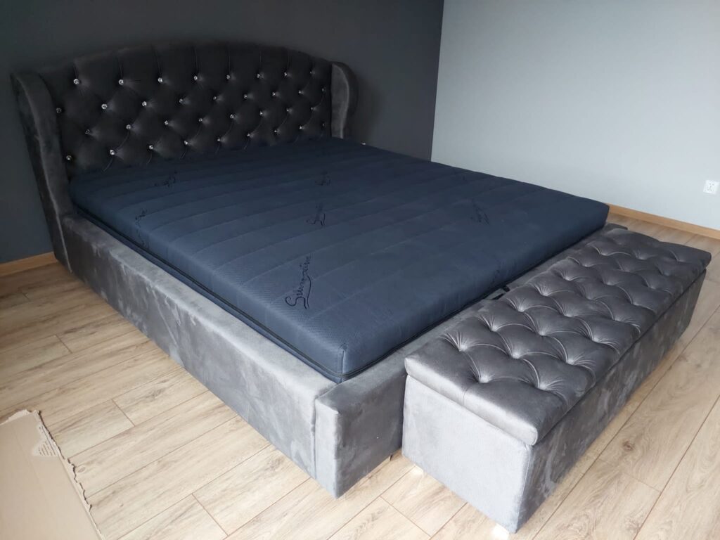 Łóżko z eleganckim czarnym zagłówkiem i podnóżkiem, elegancko zaprojektowane z myślą o estetyce nowoczesnej sypialni.